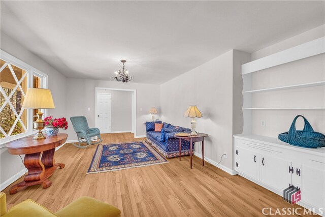 living area with a chandelier, light wood-style flooring, and baseboards