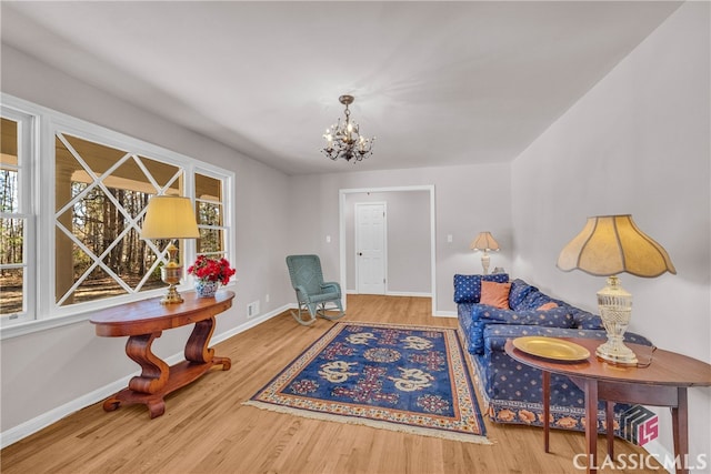 sitting room featuring baseboards, a chandelier, and wood finished floors