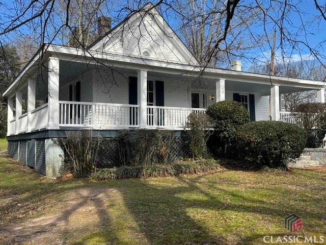 view of side of property with covered porch and a lawn