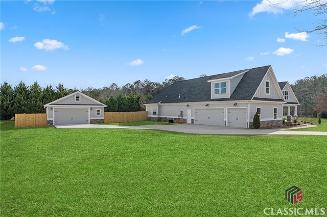 exterior space with a garage, driveway, fence, board and batten siding, and a front yard