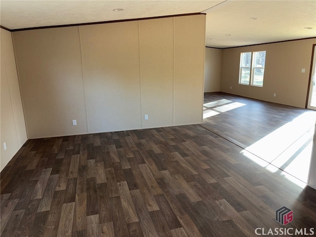 empty room with crown molding and wood finished floors