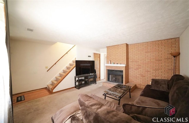 living room with brick wall, carpet, a brick fireplace, and a textured ceiling