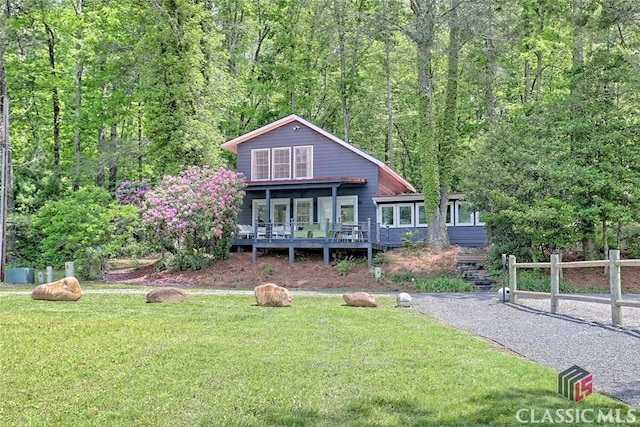 view of front of house featuring a view of trees, fence, driveway, and a front lawn