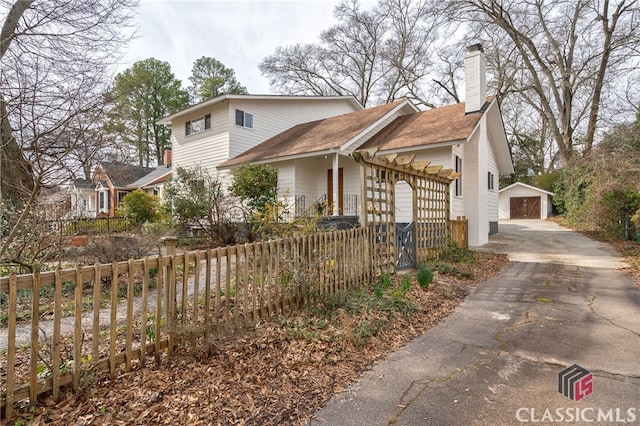 view of side of property with a chimney, a fenced front yard, and an outdoor structure