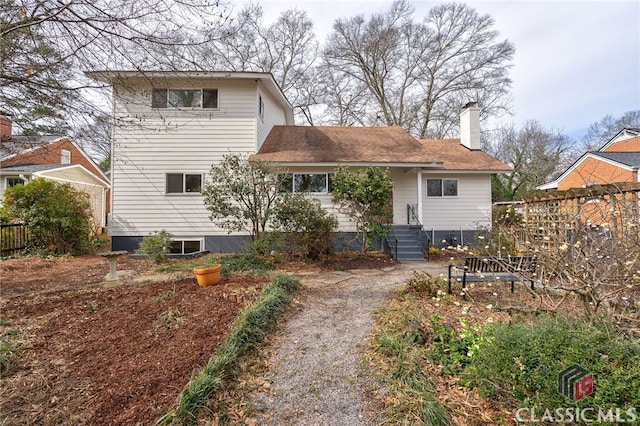 back of house featuring fence and a chimney