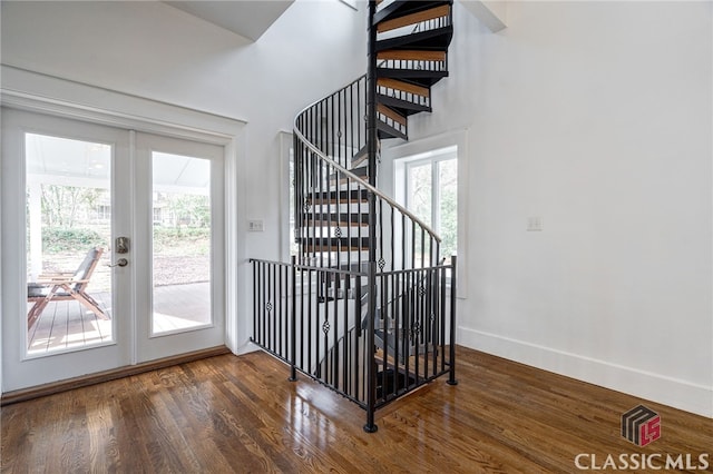 stairs featuring french doors, plenty of natural light, and wood finished floors