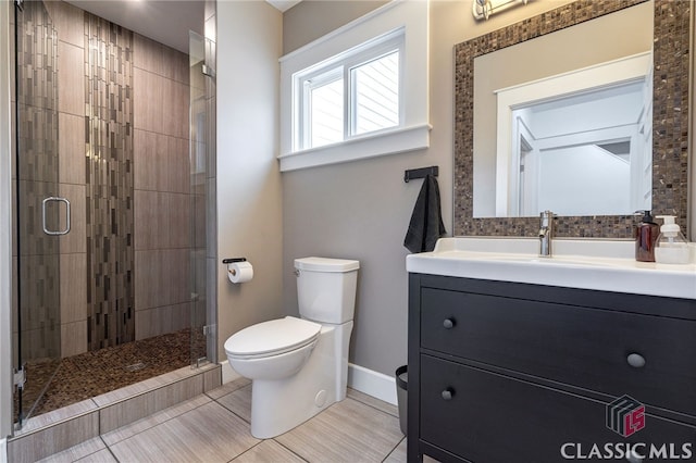 bathroom featuring toilet, a stall shower, baseboards, and vanity