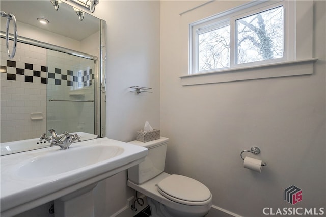 full bathroom featuring tiled shower, toilet, and baseboards