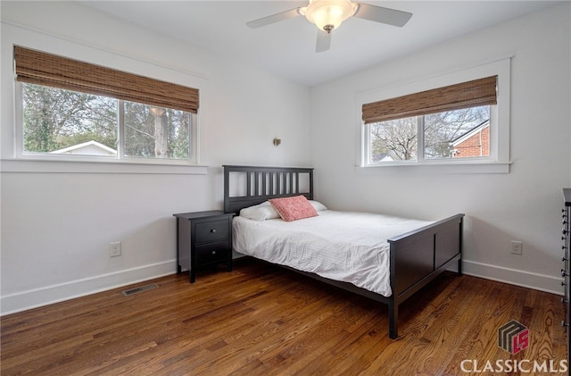 bedroom featuring a ceiling fan, visible vents, dark wood finished floors, and baseboards