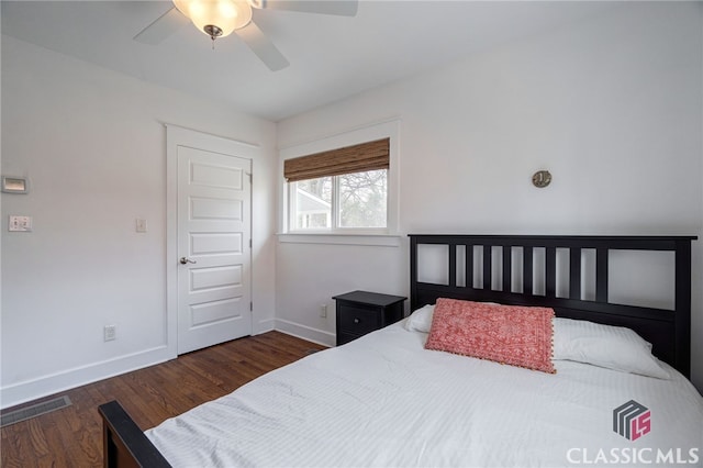 bedroom featuring a ceiling fan, dark wood-style flooring, visible vents, and baseboards