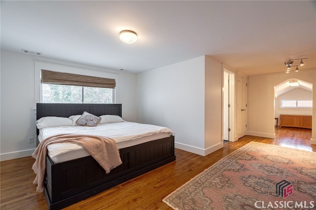 bedroom with baseboards, visible vents, and wood finished floors