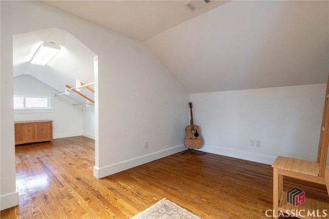 additional living space with visible vents, vaulted ceiling, light wood-style flooring, and baseboards