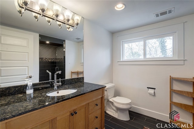 full bathroom featuring toilet, vanity, visible vents, baseboards, and a stall shower