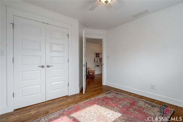 bedroom with dark wood-type flooring, a closet, visible vents, and baseboards