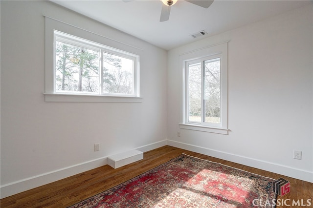 unfurnished room featuring ceiling fan, wood finished floors, visible vents, and baseboards