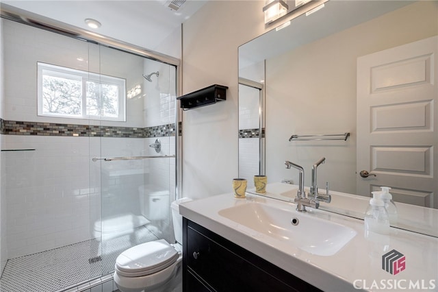 full bathroom featuring toilet, vanity, a shower stall, and visible vents