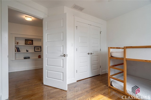 unfurnished bedroom featuring dark wood-style floors, baseboards, visible vents, and a closet