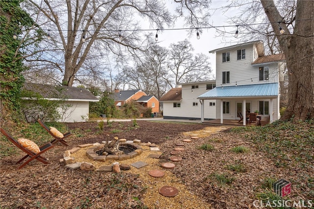 back of property with a patio area, an outdoor fire pit, and metal roof