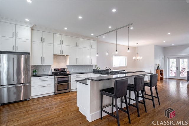 kitchen with a peninsula, a breakfast bar, white cabinetry, french doors, and appliances with stainless steel finishes