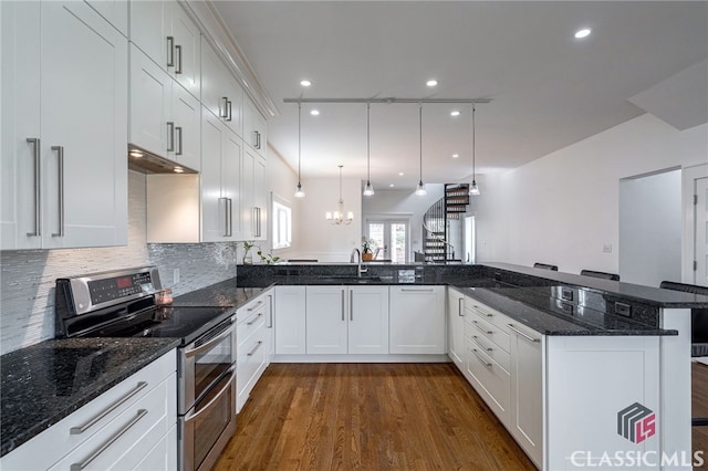 kitchen featuring a peninsula, pendant lighting, range with two ovens, and dark stone countertops