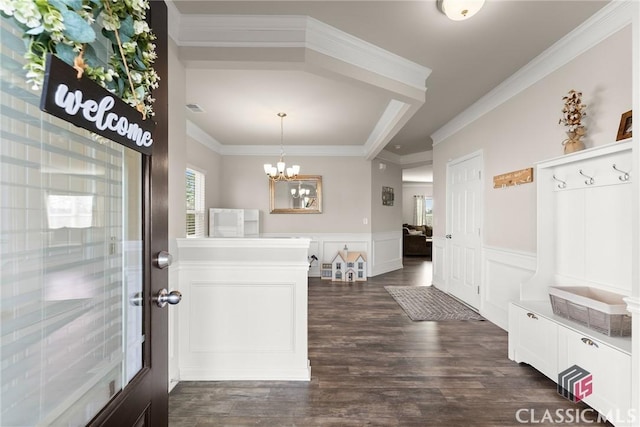 interior space featuring a notable chandelier, a wainscoted wall, dark wood-type flooring, visible vents, and ornamental molding