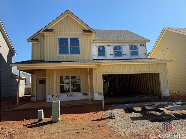 property in mid-construction with board and batten siding and a shingled roof