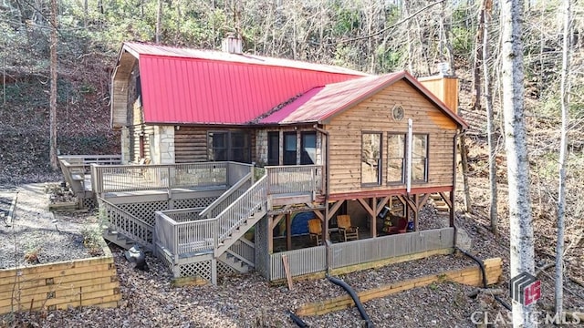 back of property with stairs, a chimney, metal roof, and a wooden deck