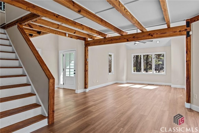 unfurnished living room with vaulted ceiling with beams, light wood-style floors, stairs, and baseboards