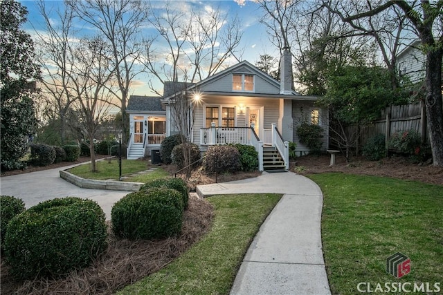 bungalow-style home with a sunroom, a yard, a chimney, and fence