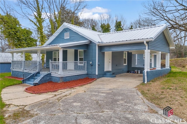 view of front of home with covered porch, metal roof, a carport, and driveway