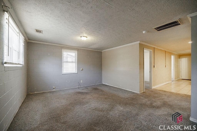 unfurnished room with ornamental molding, light colored carpet, visible vents, and concrete block wall