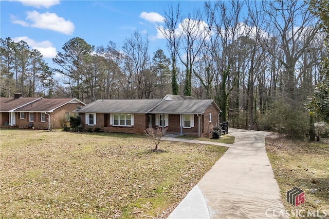 view of front of property with driveway, brick siding, and a front lawn