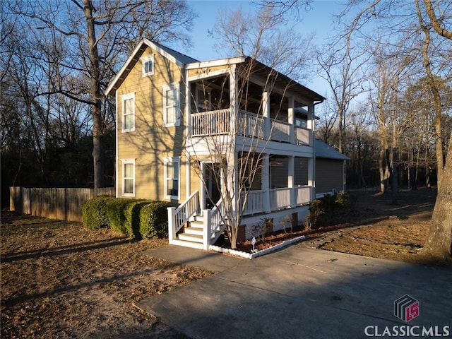 view of front of home with fence and a balcony