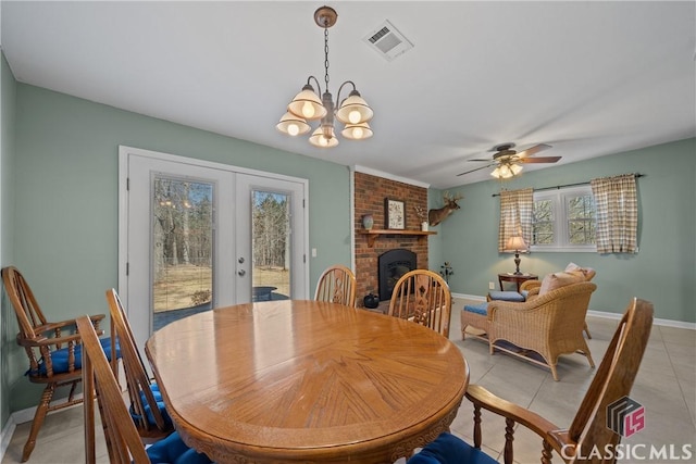 dining room with baseboards, visible vents, french doors, a brick fireplace, and light tile patterned flooring