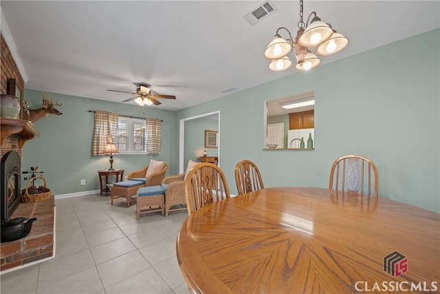 dining space with a fireplace, light tile patterned floors, visible vents, baseboards, and ceiling fan with notable chandelier