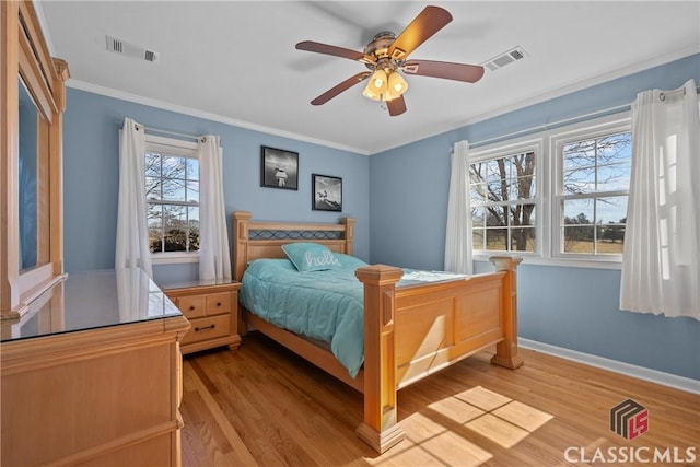 bedroom featuring light wood-type flooring, visible vents, crown molding, and baseboards