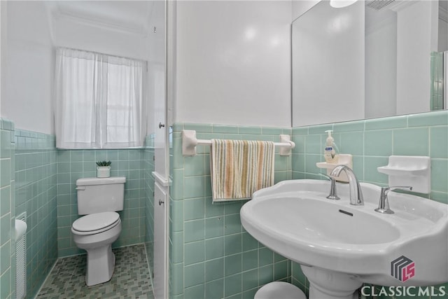 bathroom with toilet, a wainscoted wall, radiator heating unit, tile patterned flooring, and a sink