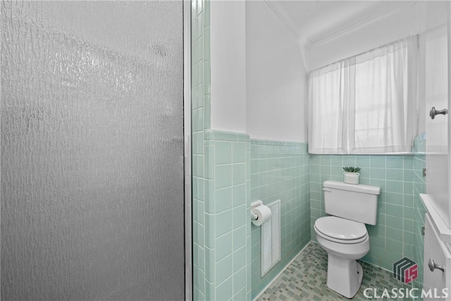 full bathroom featuring tile walls, visible vents, toilet, a shower with shower door, and tile patterned floors