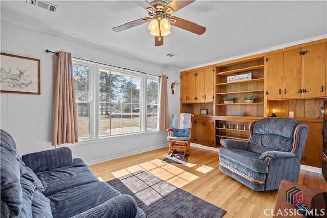 living room featuring light wood-style floors, visible vents, and ornamental molding