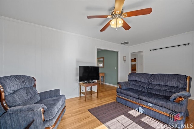 living area featuring ceiling fan, wood finished floors, visible vents, and crown molding