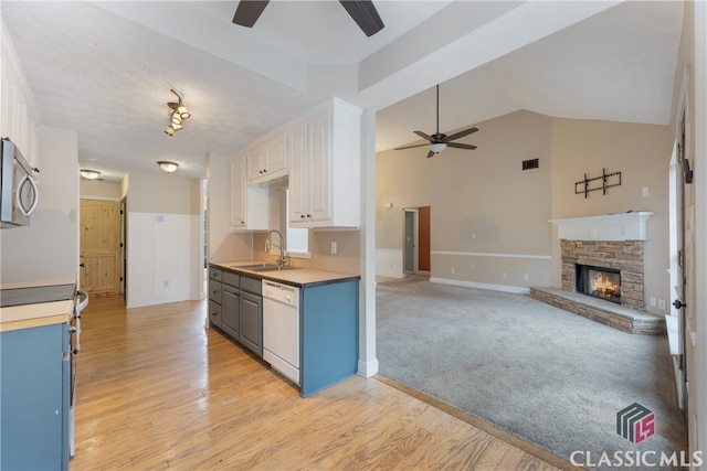 kitchen with light countertops, appliances with stainless steel finishes, open floor plan, white cabinets, and a sink