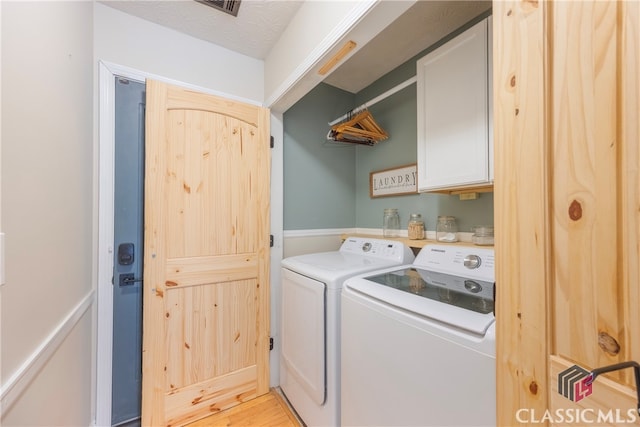 laundry area with light wood-type flooring, washer and dryer, and cabinet space