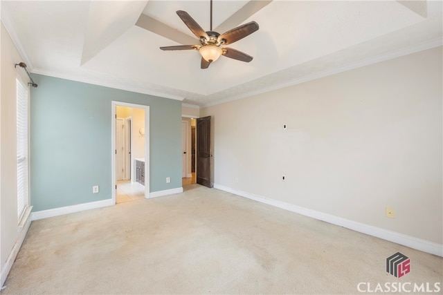 unfurnished bedroom with light carpet, baseboards, ornamental molding, a tray ceiling, and ensuite bath