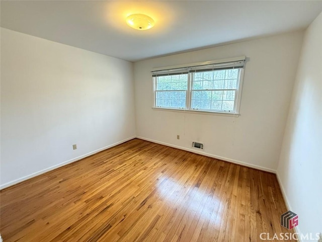 unfurnished room with baseboards, visible vents, and hardwood / wood-style flooring