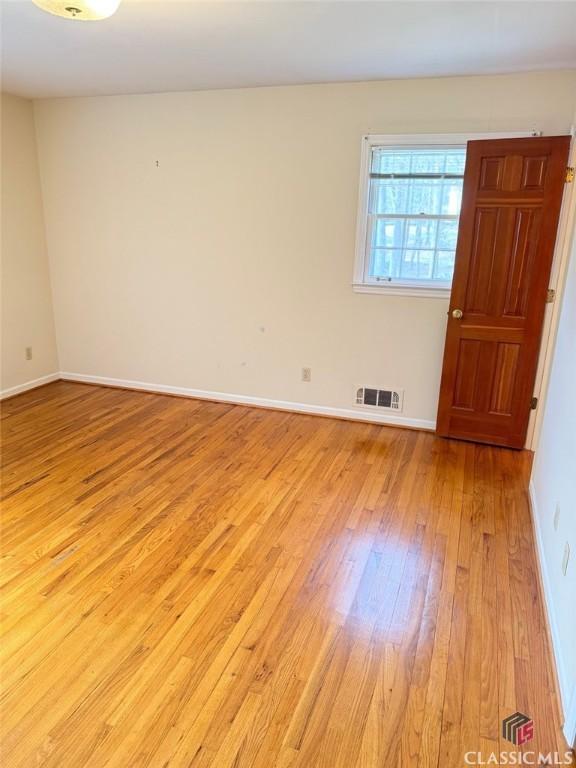 unfurnished room featuring light wood-style floors, baseboards, and visible vents