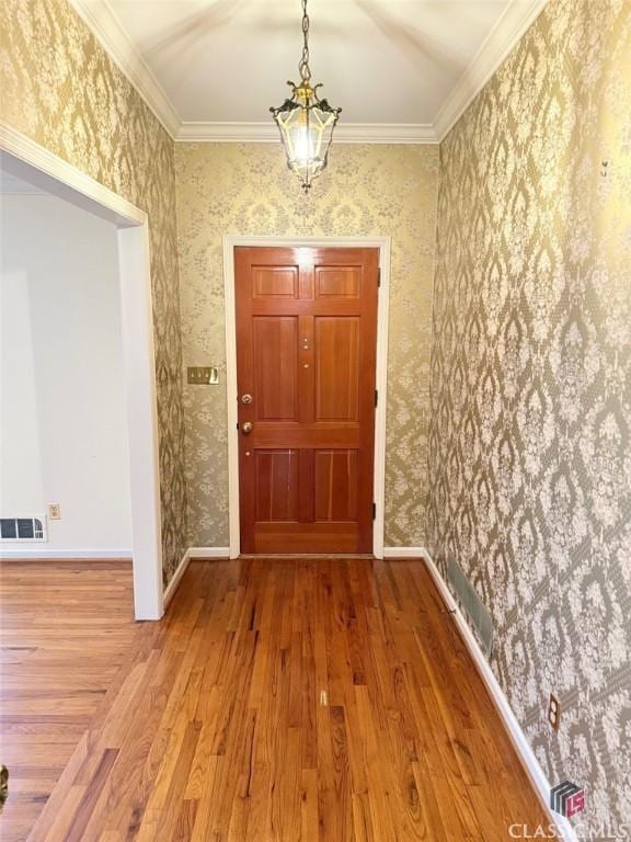 doorway to outside with baseboards, wood finished floors, visible vents, and wallpapered walls