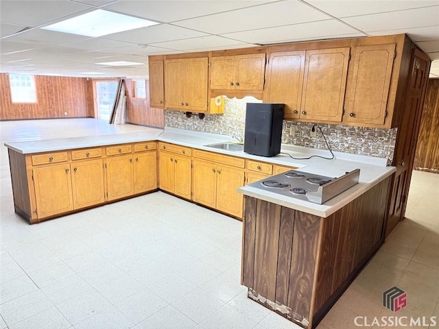 kitchen featuring brown cabinets, light floors, light countertops, a sink, and a peninsula