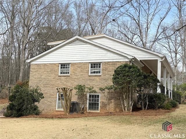 view of property exterior featuring brick siding, a yard, and central AC