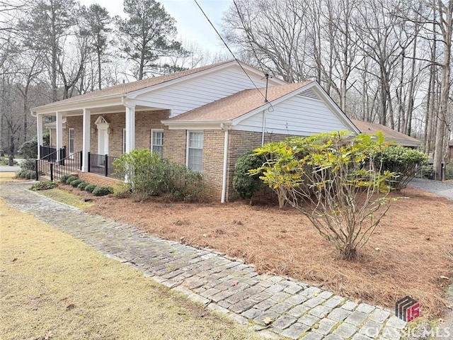 view of side of home with covered porch and brick siding