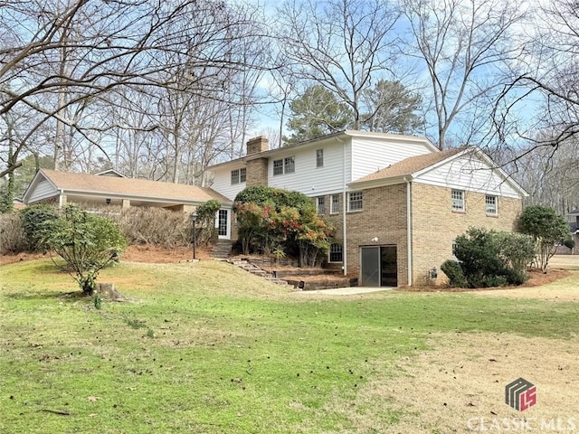 rear view of house with brick siding, a yard, and a chimney